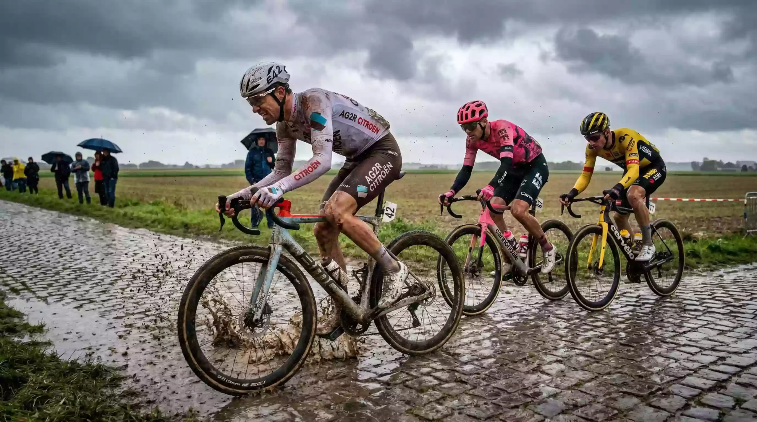 Ciclistas rodando sobre un tramo de adoquines en un día lluvioso en el norte de Francia