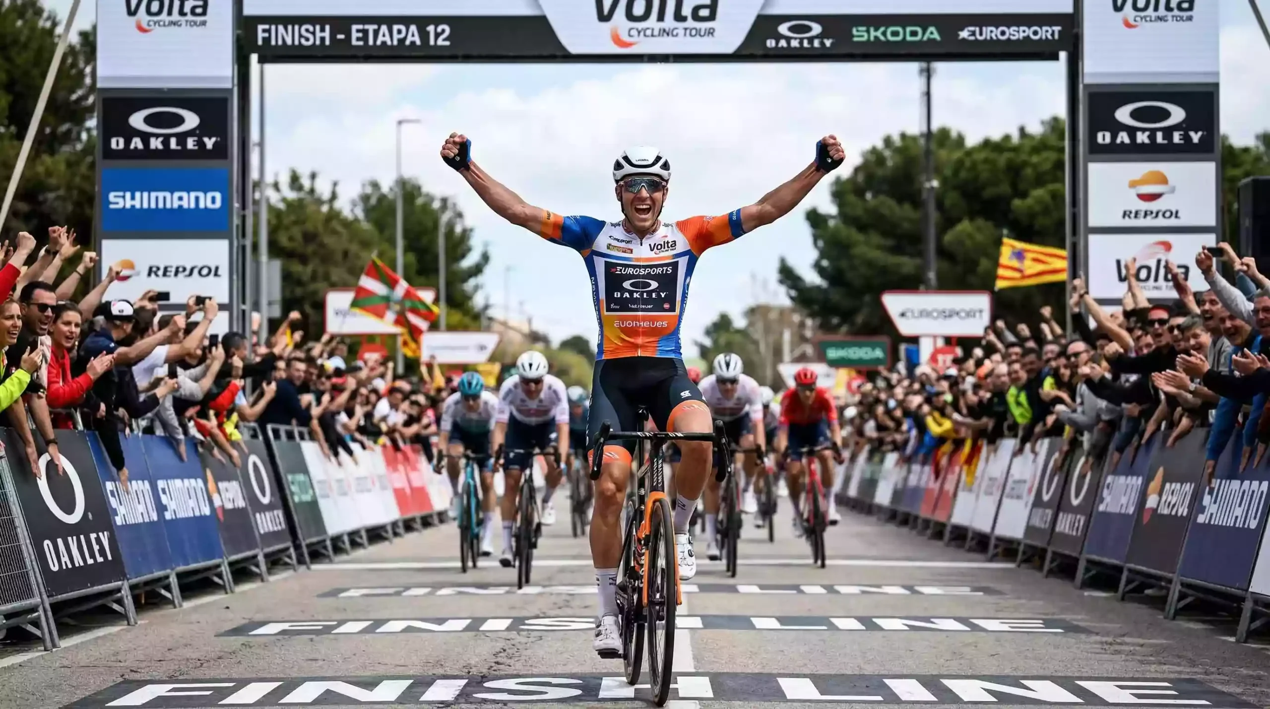 Ciclista profesional cruzando la meta de una etapa con los brazos en alto